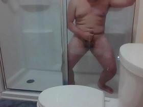 A young Asian guy indulges in self-pleasure in a hotel shower, his chubby frame jiggling as he strokes his big cock, culminating in a satisfying climax onto his round ass.
